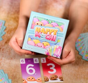 deux mains tenant la boîte du jeu de société happy mochi 