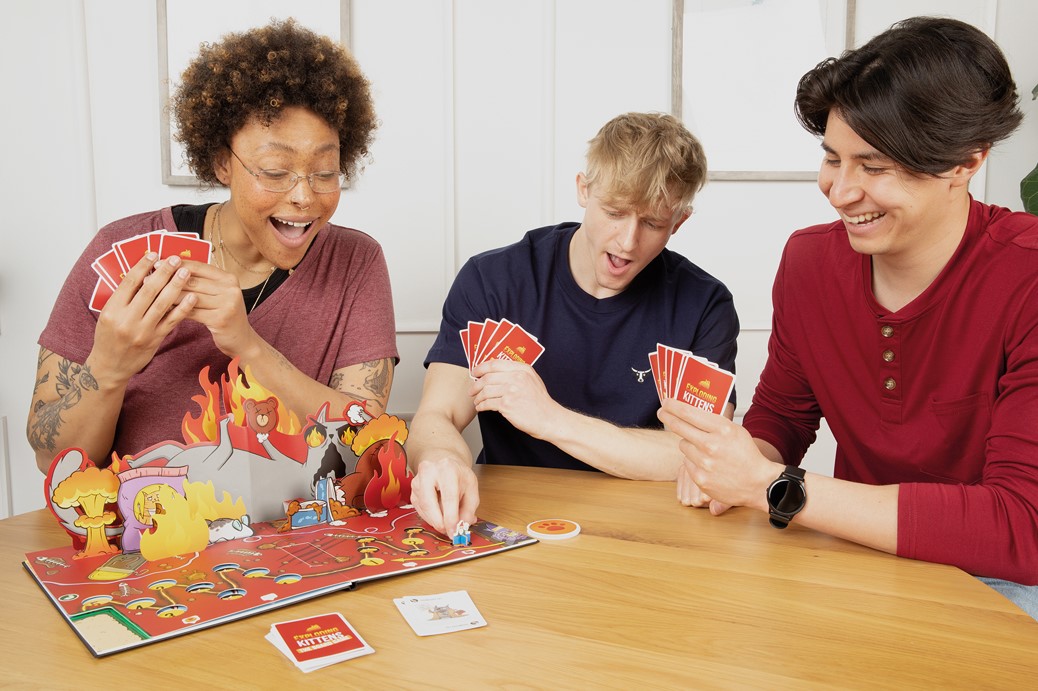 3 joueurs en pleine partie d'exploding kittens le jeu de plateau