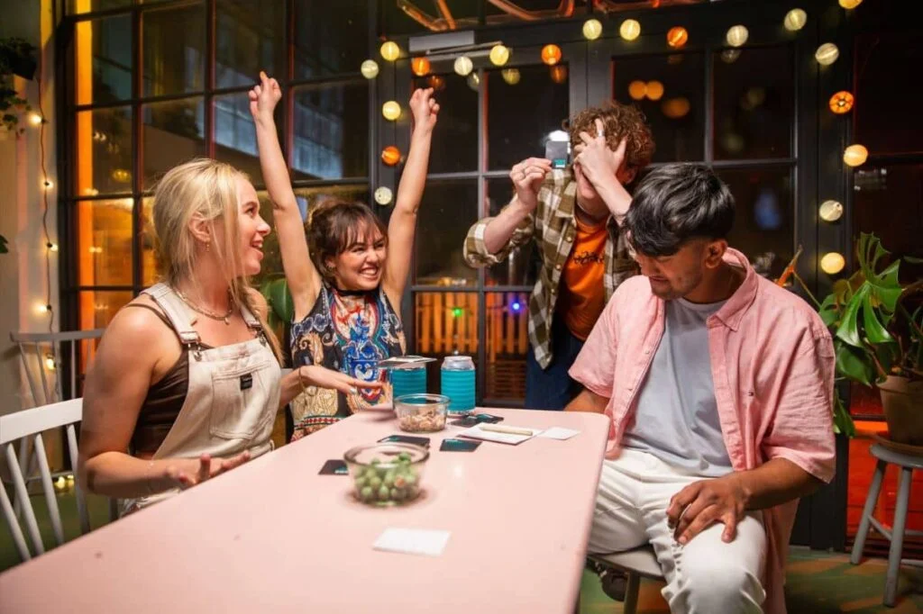 Personnes jouant à un jeu de société, en intérieur, de nuit.
