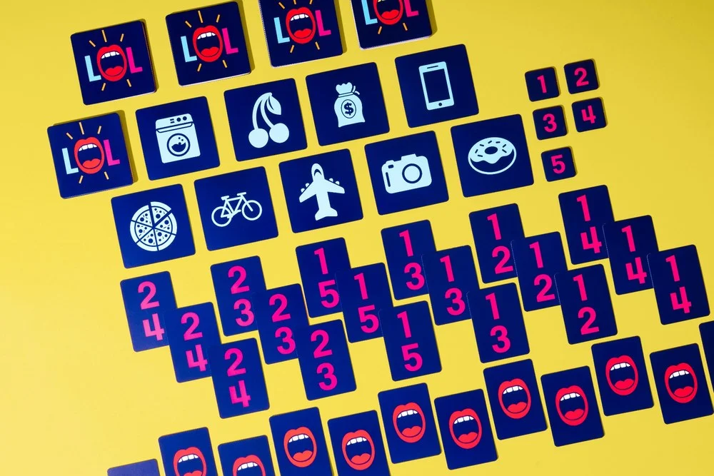 Moodbox Games Link Out Loud party game components laid out on a yellow background, showing LOL cards, picture icon cards, numbered answer tiles, and mouth logo cards for a fast word association game.